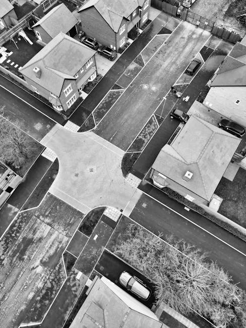 An aerial view taken from a drone showing a residential neighbourhood with a mix of detached and semi-detached houses, many with pitched roofs and small gardens surrounded by fences and hedges. Severa